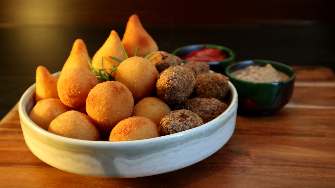 Traditional Brazilian snacks coxinha and quibe on wooden dark background. Selective focus.
